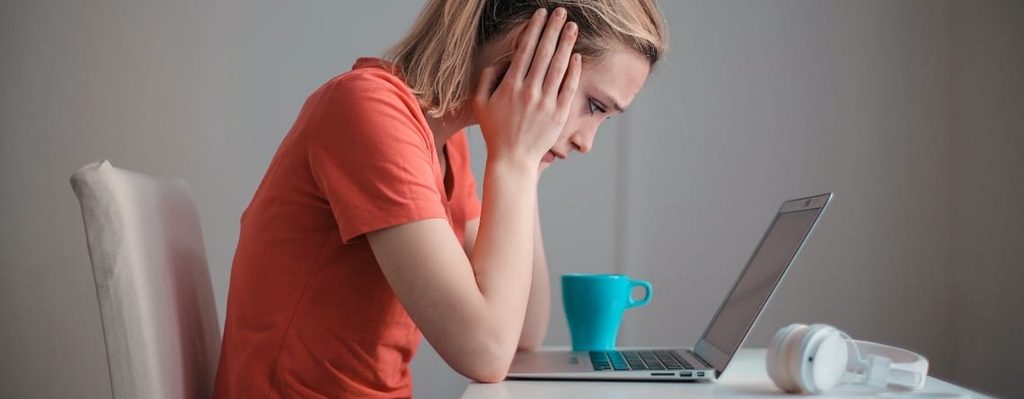 An image showing a girl with a laptop feeling stressed