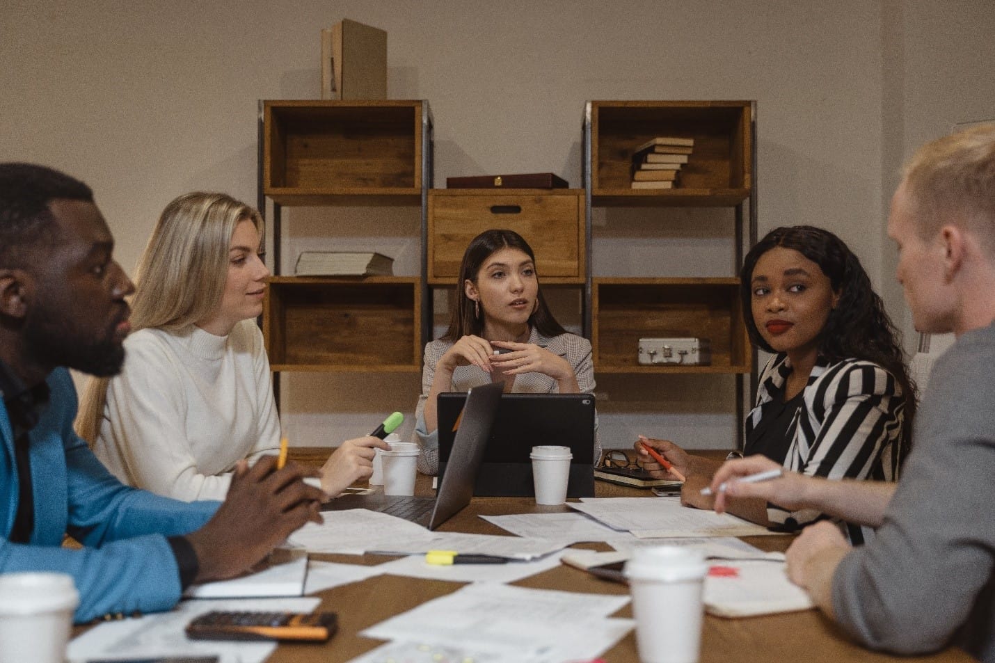 A group of people discussing the various essay writing services while sitting around a table in an office.