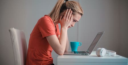 An image showing a girl with a laptop feeling stressed