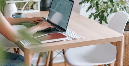 A student in UK brainstorming ideas for her perfect essay while working on her laptop at home.