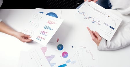 Two people sitting at a table and analyzing statistical graphs.