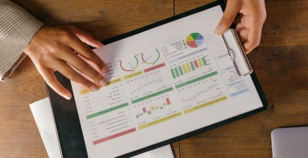 A student analyzing the differences between qualitative and quantitative data through several graphs and charts printed and pasted on a clipboard.
