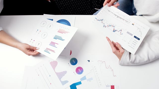Two people sitting at a table and analyzing statistical graphs.