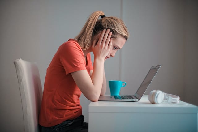 An image showing a girl with a laptop feeling stressed